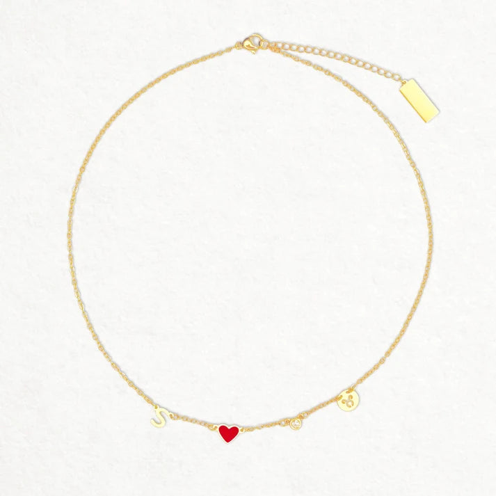 Collana con cuore rosso, iniziale, pietra e segno zodiacale su fondo bianco